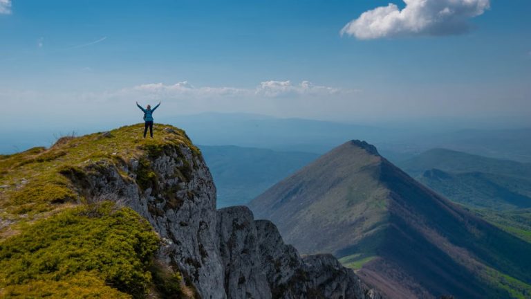 A person celebrating victory atop a mountain peak in Serbia with breathtaking views.